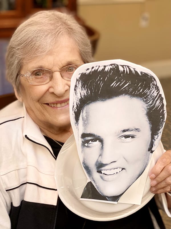 Resident holding a fun cutout of Elvis Presley