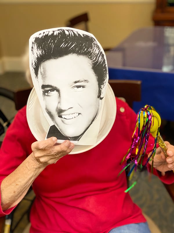 Resident celebrating with an Elvis mask and colorful decorations