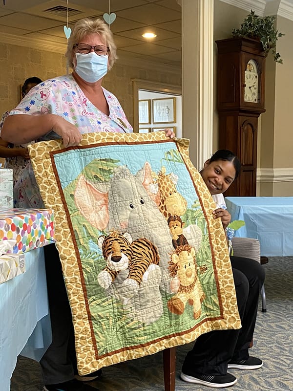 Staff member presenting a colorful quilt during an event