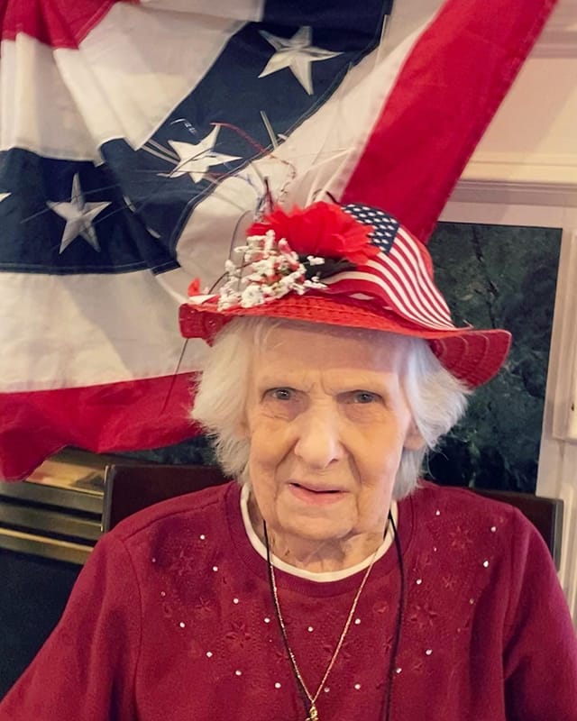 Resident wearing a patriotic hat with an American flag backdrop