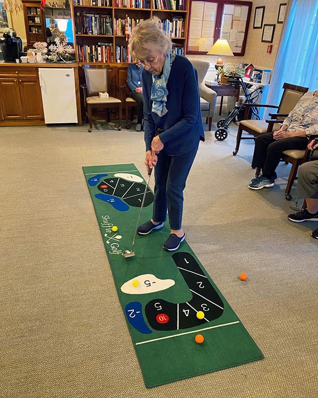 Resident playing mini-golf in a lively common area