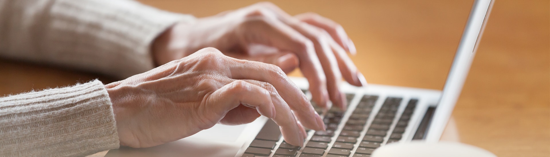 Close-up of hands typing on a laptop keyboard