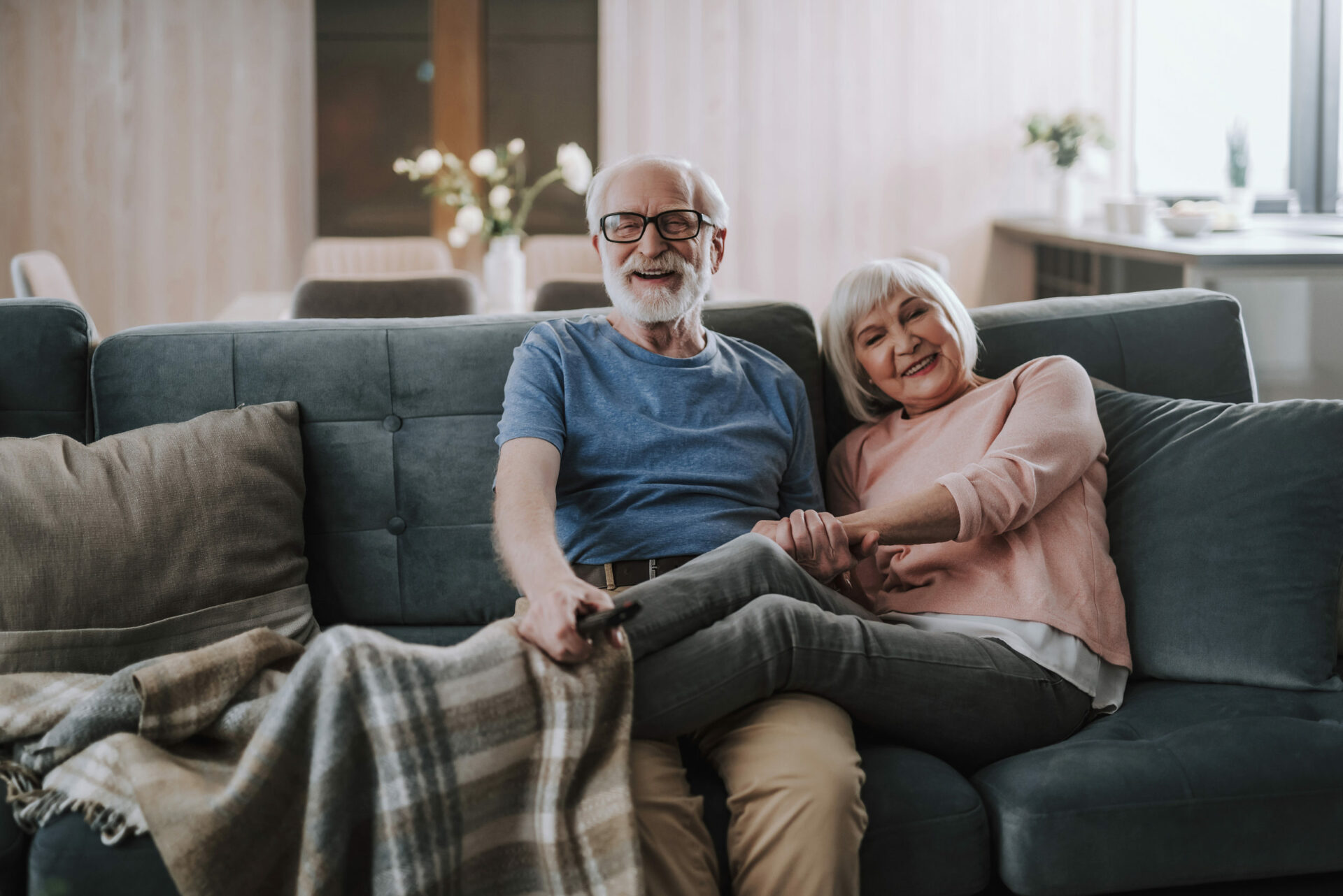 Elderly couple smiling and sitting on a couch