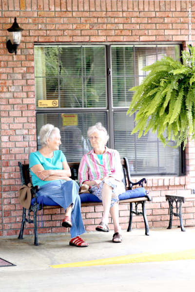 Two senior women chatting on a bench outside