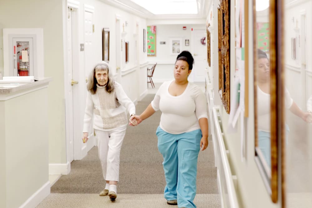 A staff member assisting a resident in a hallway
