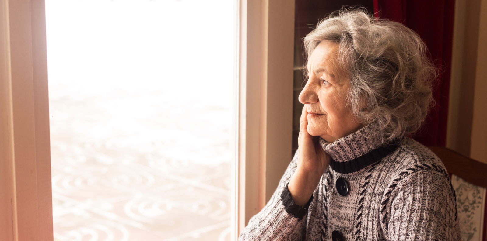 Senior woman thoughtfully looking out of a window