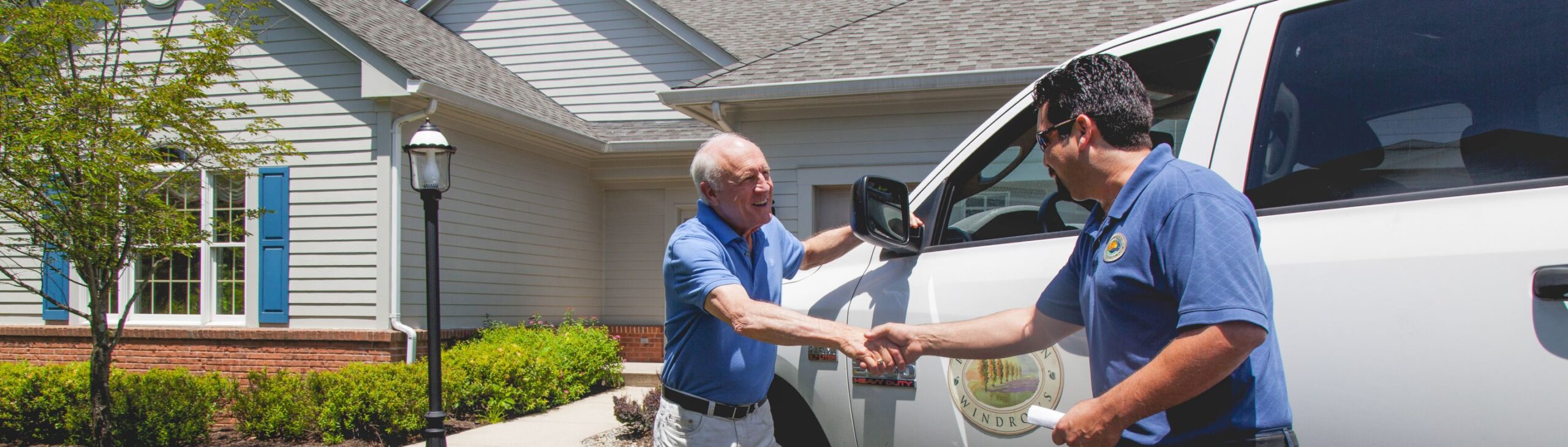 A resident shaking hands with staff outside a building