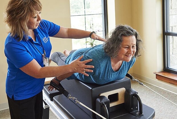 Staff assisting a resident with physical therapy in a bright room