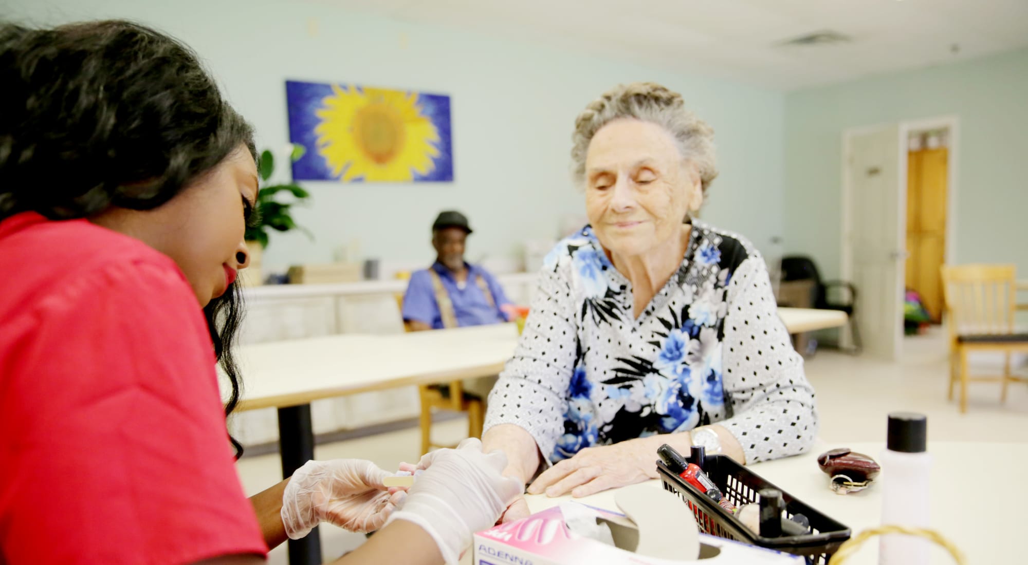 Care staff providing manicure to a resident in a common area