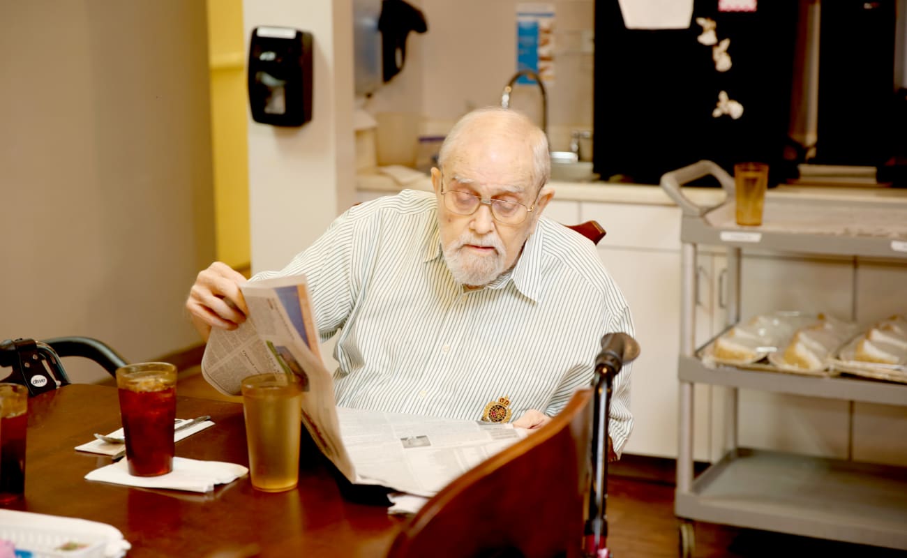 An elderly man reading a newspaper in a dining area