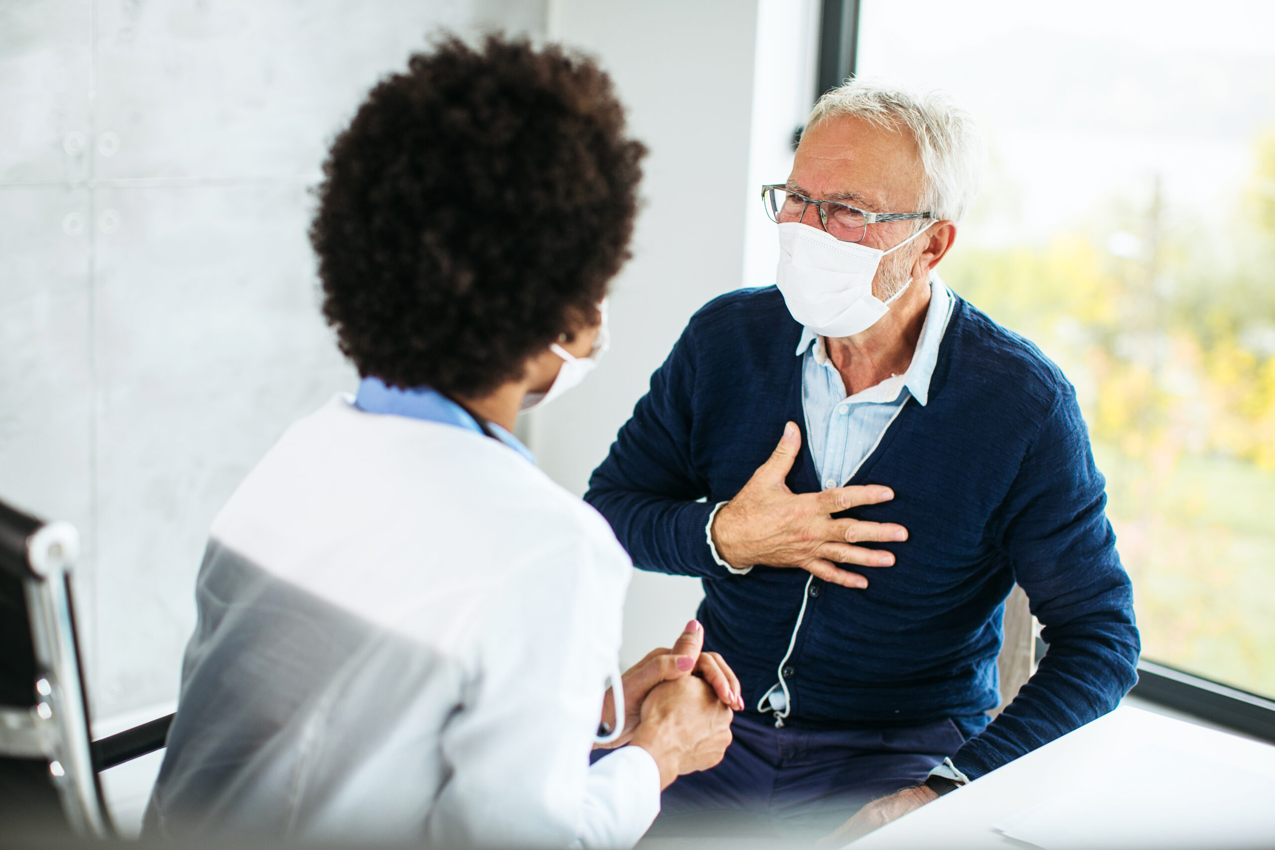 A doctor consulting with an elderly man in a medical setting