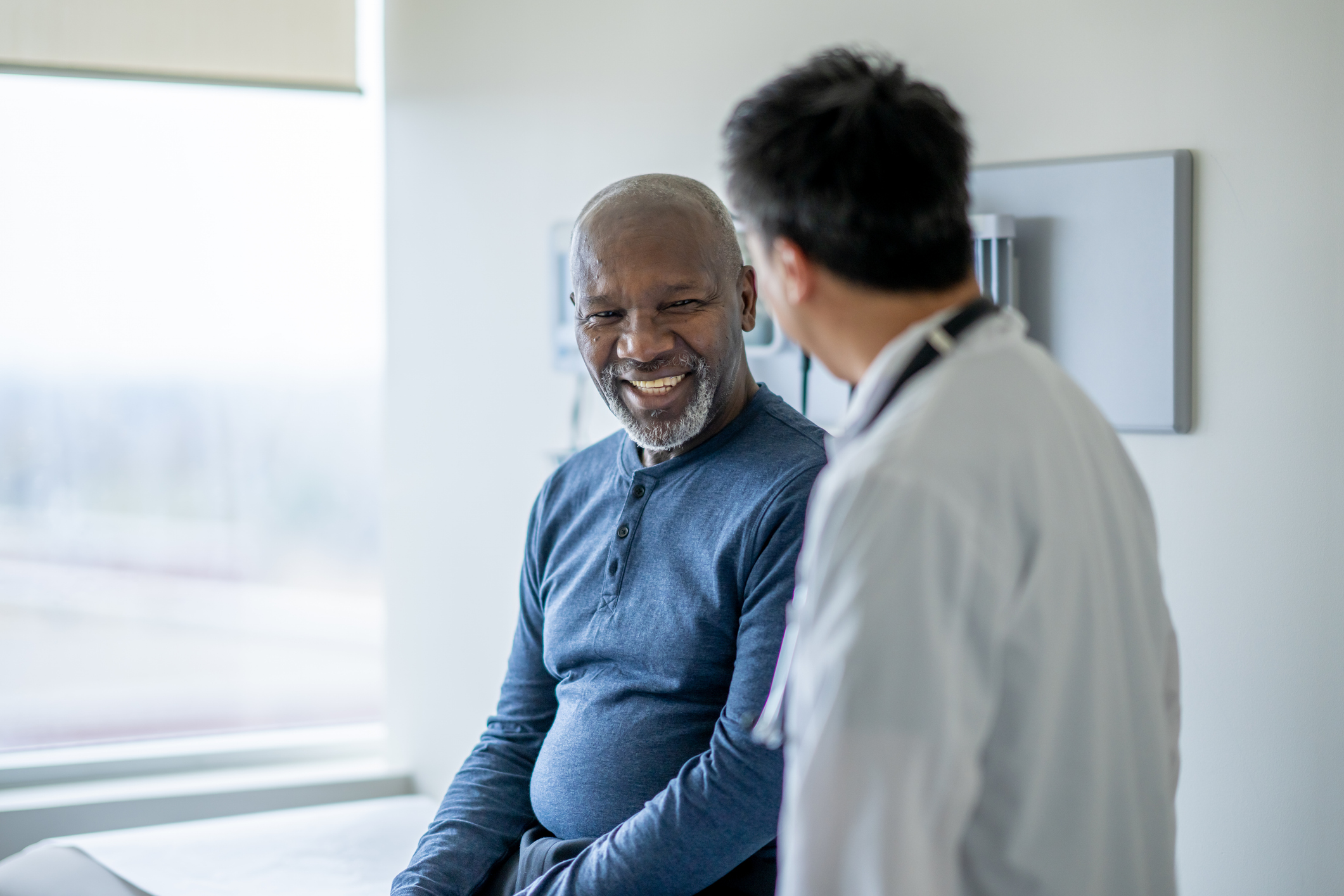 A senior man smiling with a healthcare professional