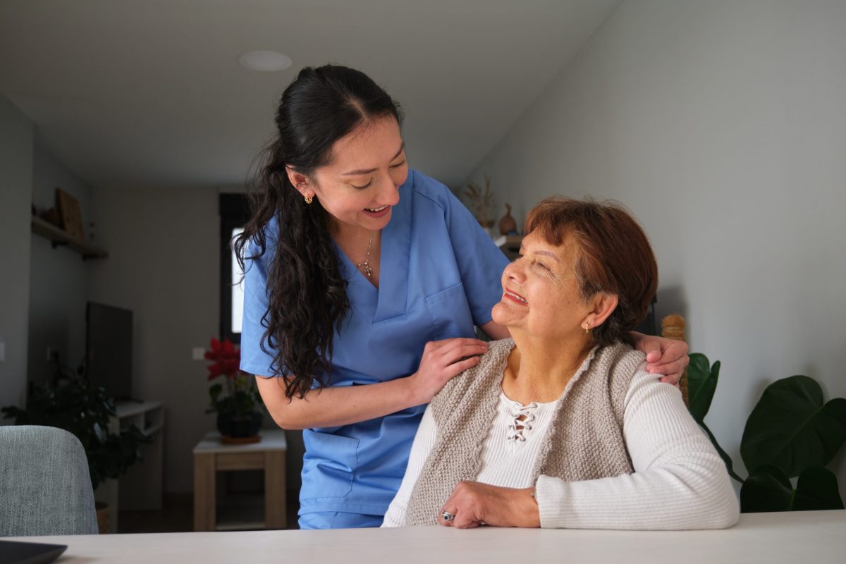 Nurse smiling and assisting a resident in a bright room