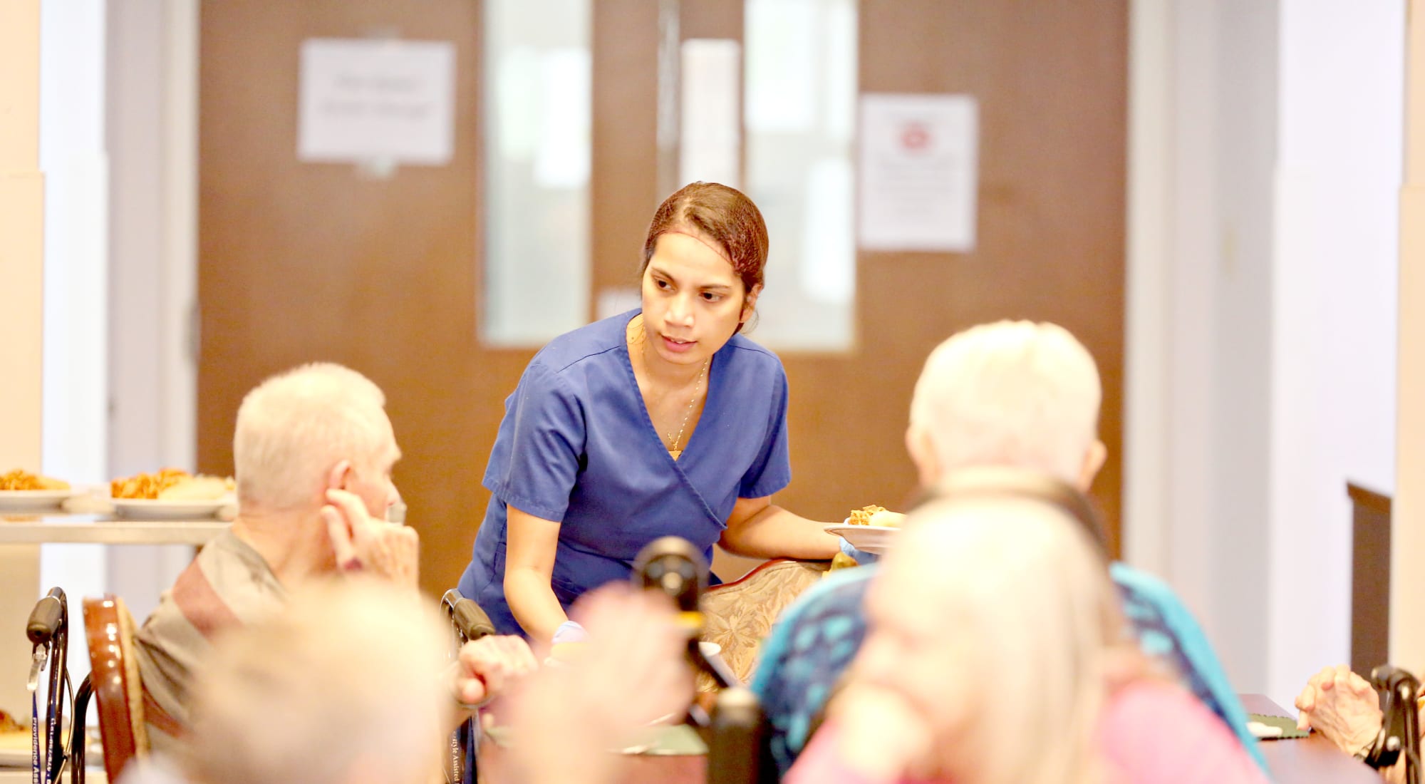 Staff serving food to residents in dining room