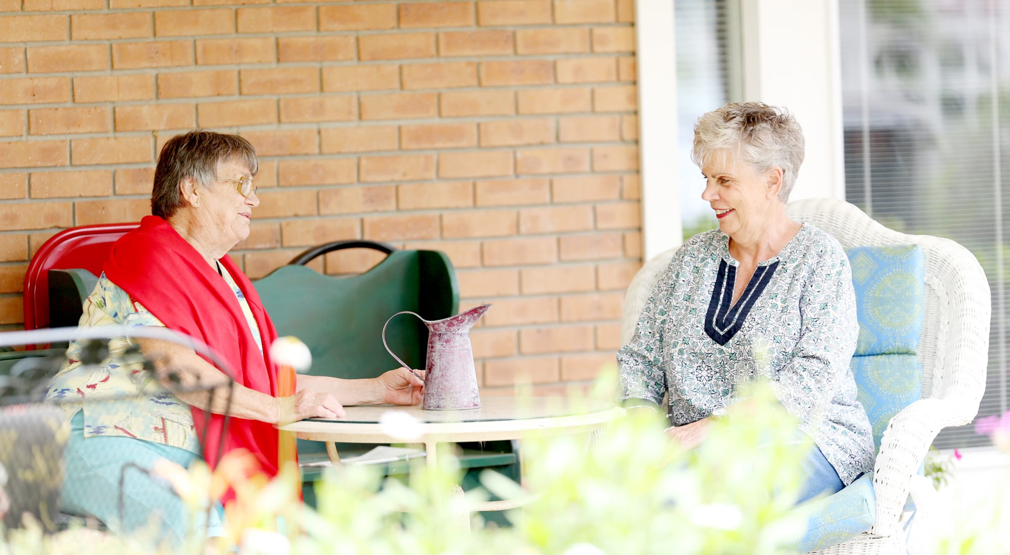 Two residents chatting on an outdoor patio