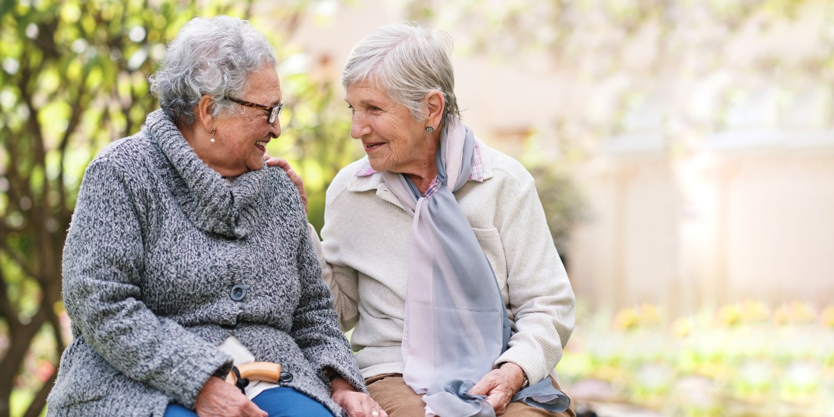 Two senior women enjoying a conversation in a garden