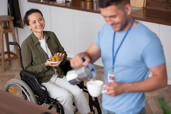 A staff member serving food to a resident in a kitchen.
