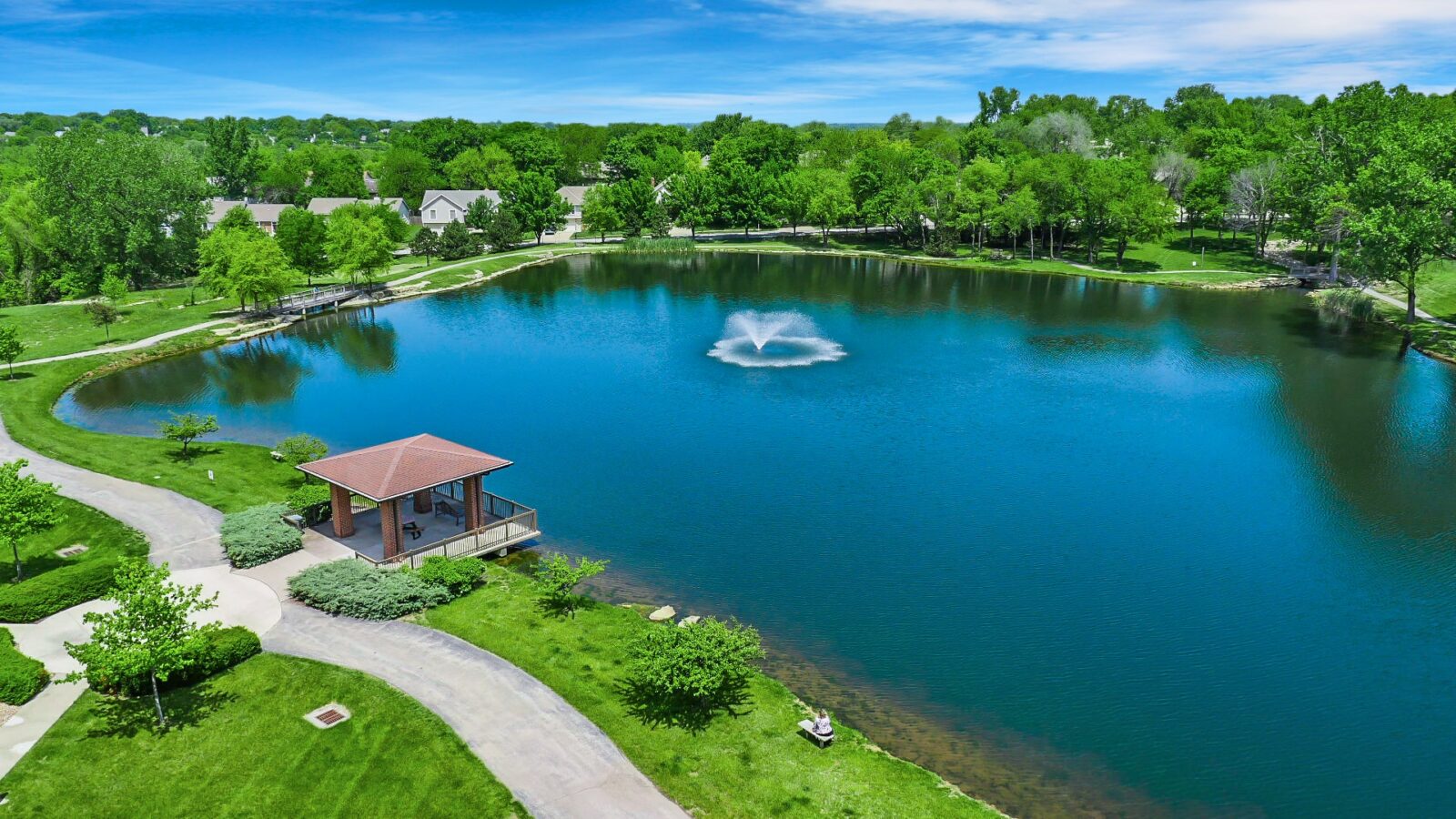 Aerial view of a serene lake with a gazebo and fountain