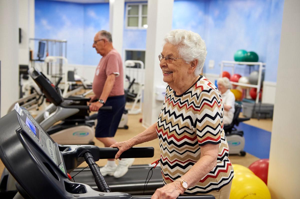 Residents exercising on treadmills in a fitness room