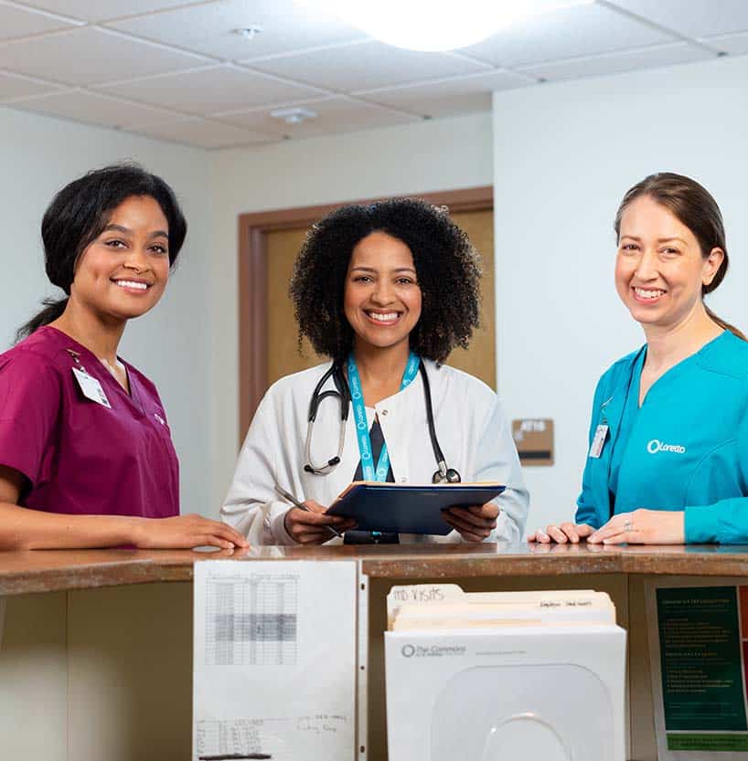 Three staff members smiling at a reception desk