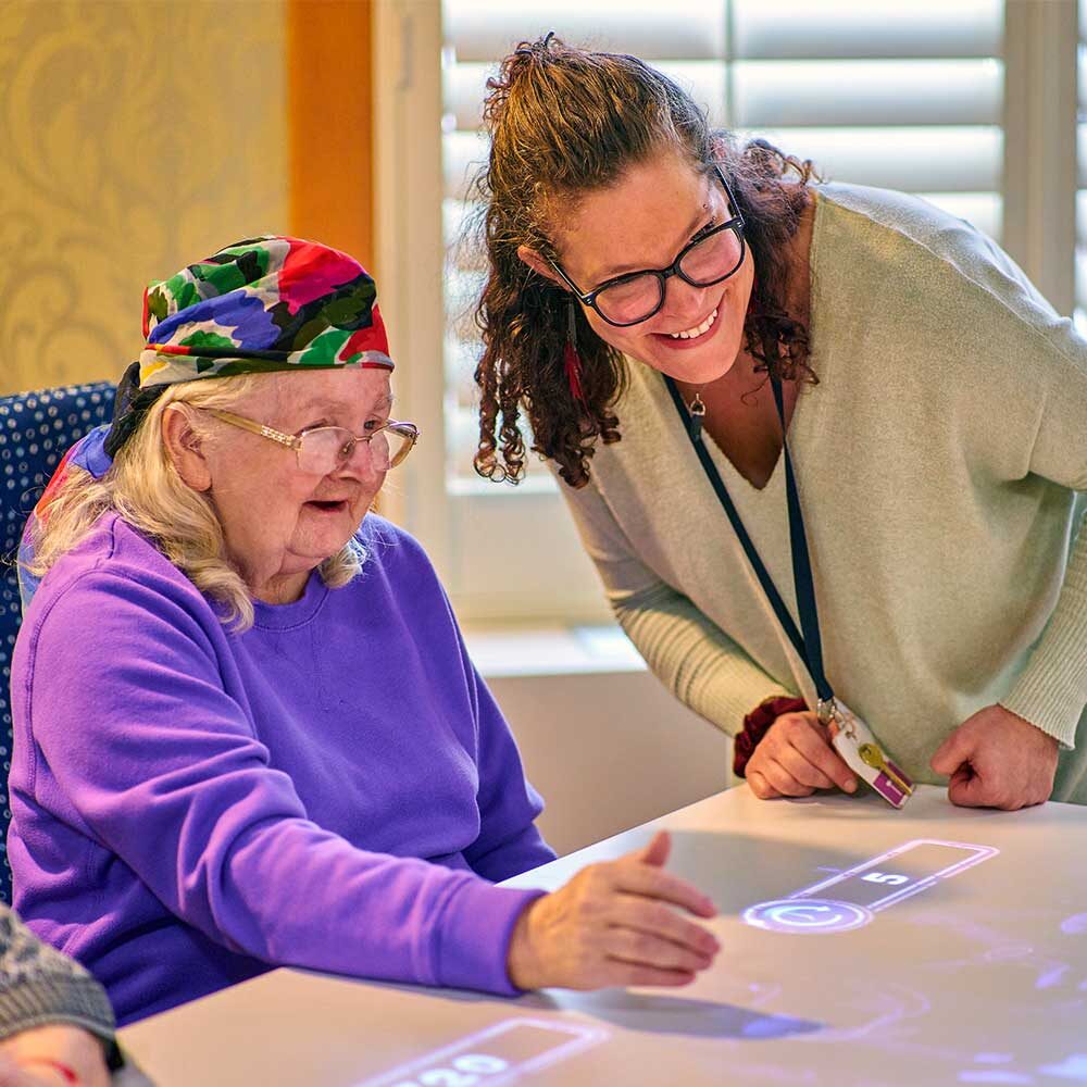 Resident engaged in an interactive activity with staff assistance