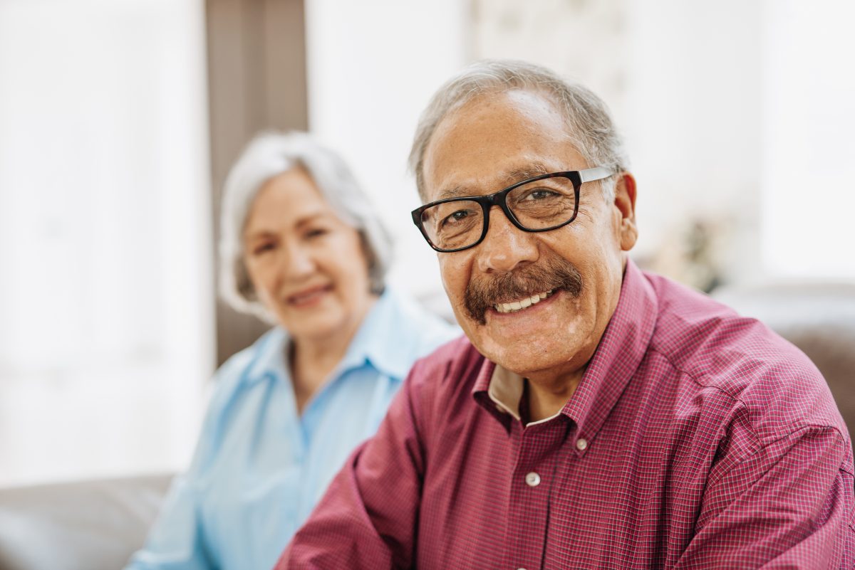 A smiling elderly couple sitting together in a cozy room
