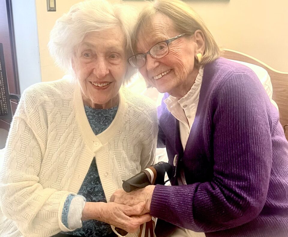 Two residents smiling and holding hands in a common area
