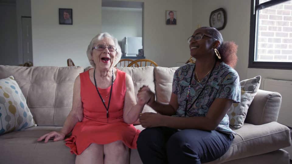 A resident and staff member enjoying a conversation on a sofa.