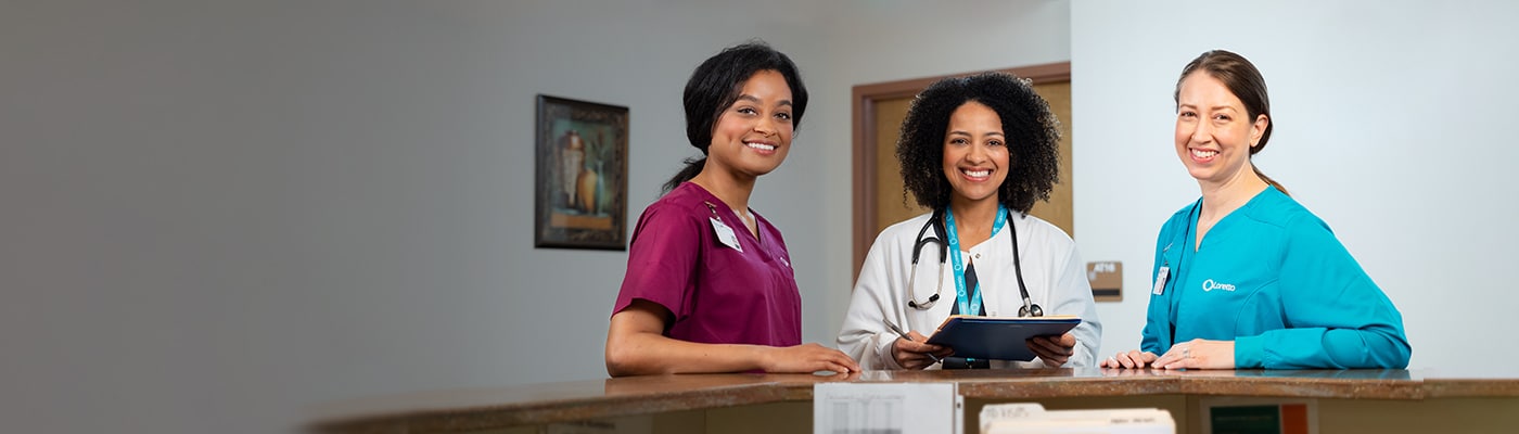 Three smiling staff members at a reception area