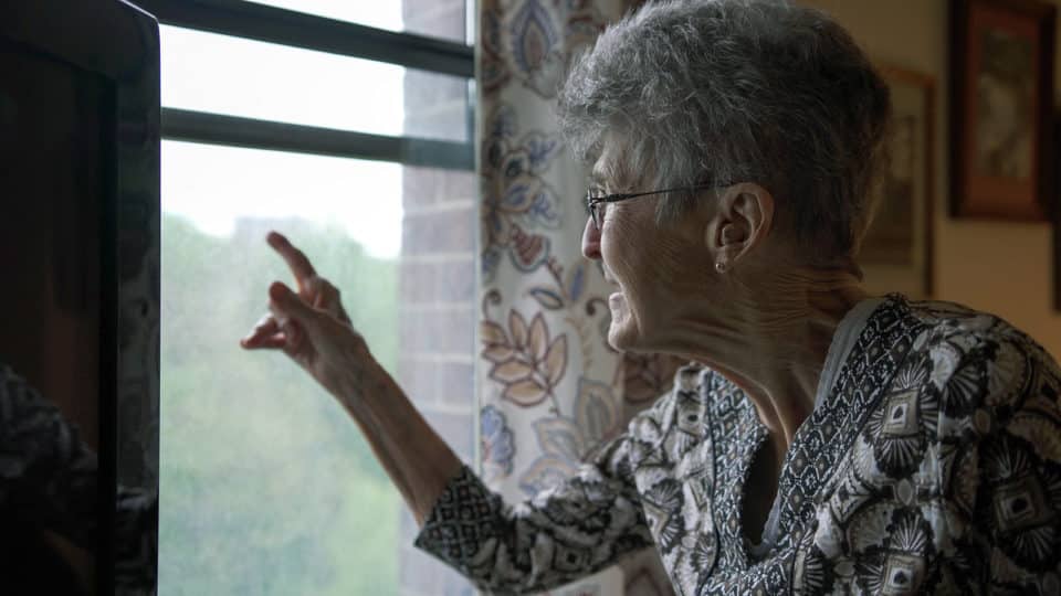 Resident pointing out the window with a smile
