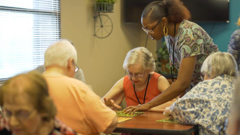 Residents playing bingo with staff assistance