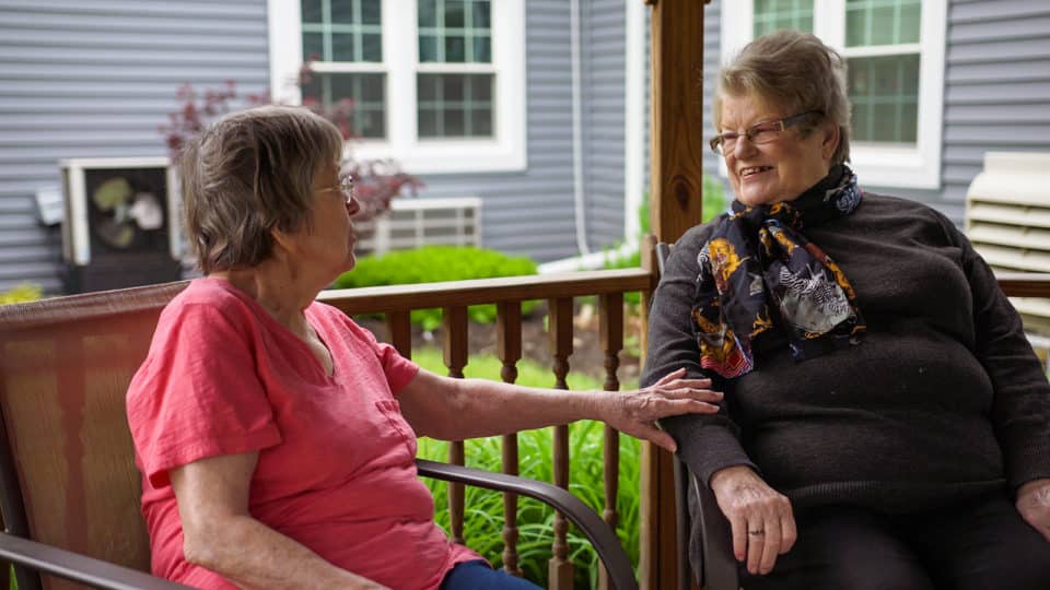 Two residents enjoying conversation on a porch