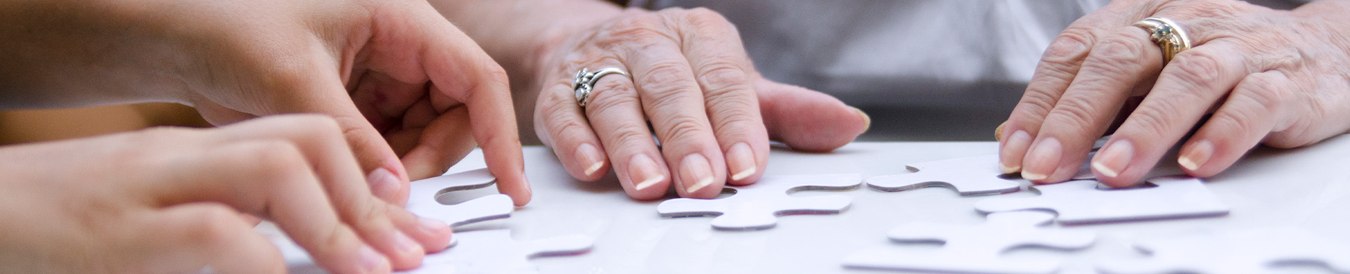 Elderly hands and young hands assembling a puzzle