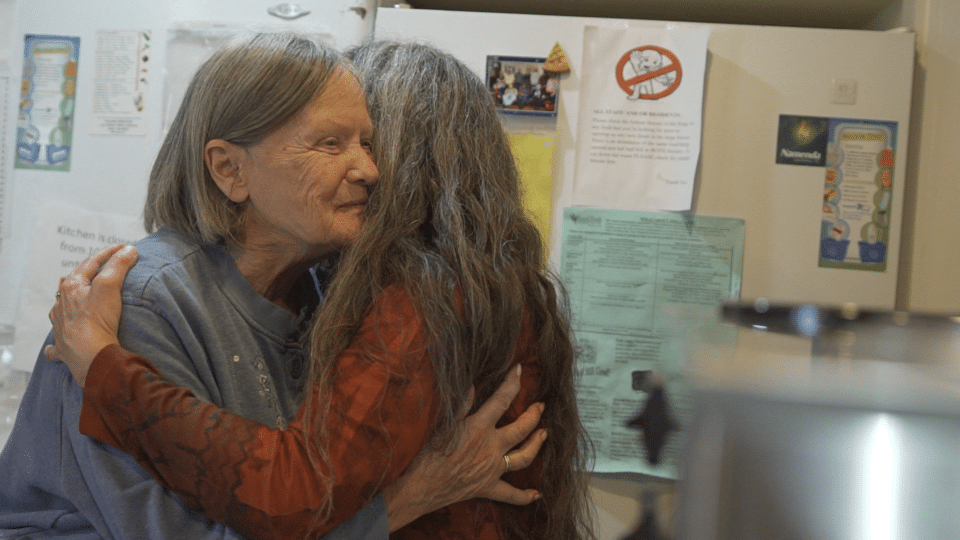 Two residents embracing in a warm indoor setting