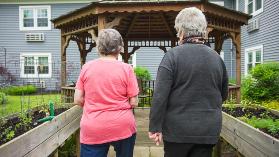 Two residents walking towards a gazebo in the garden