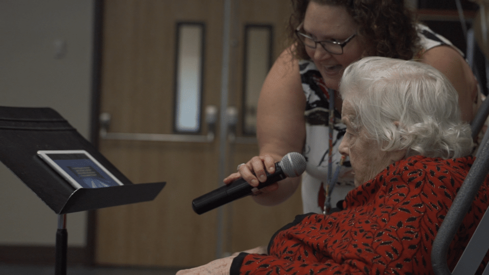 Staff member singing with a resident during an activity.