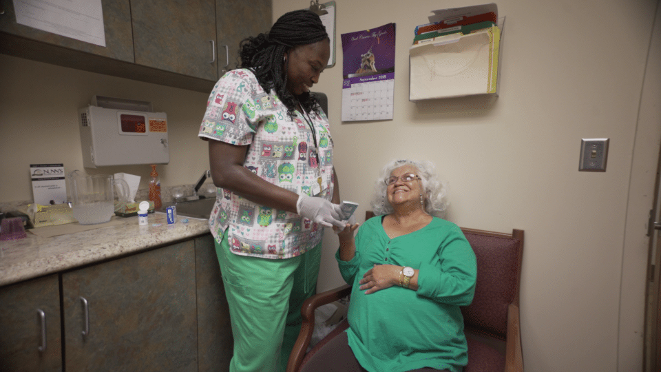A caregiver assisting a senior woman in a private room
