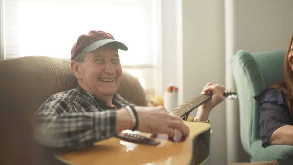 Resident playing guitar in a cozy indoor setting