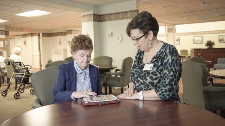 Staff assisting a resident at a communal table
