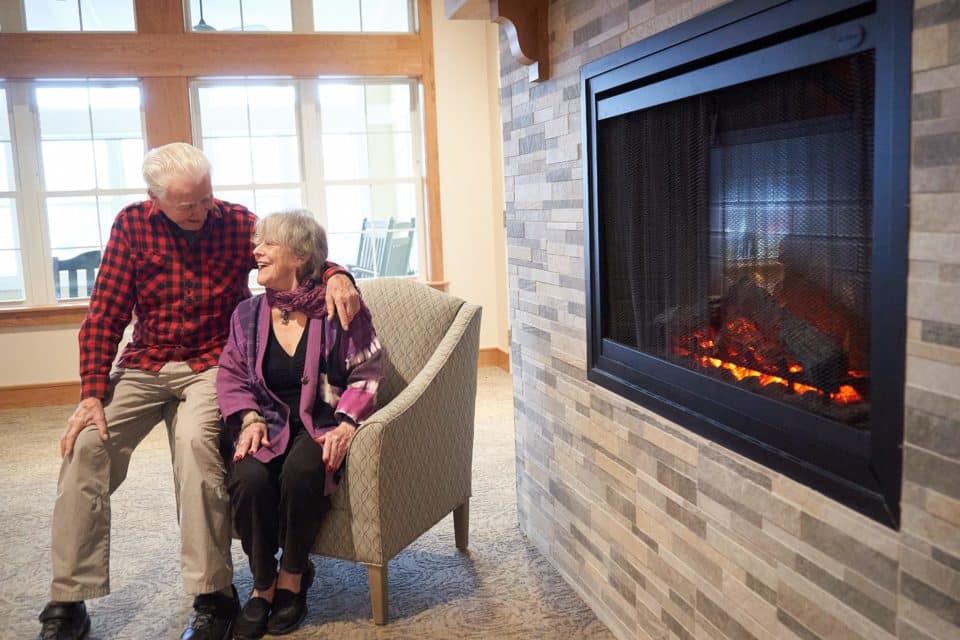 Two residents enjoying time together by a fireplace