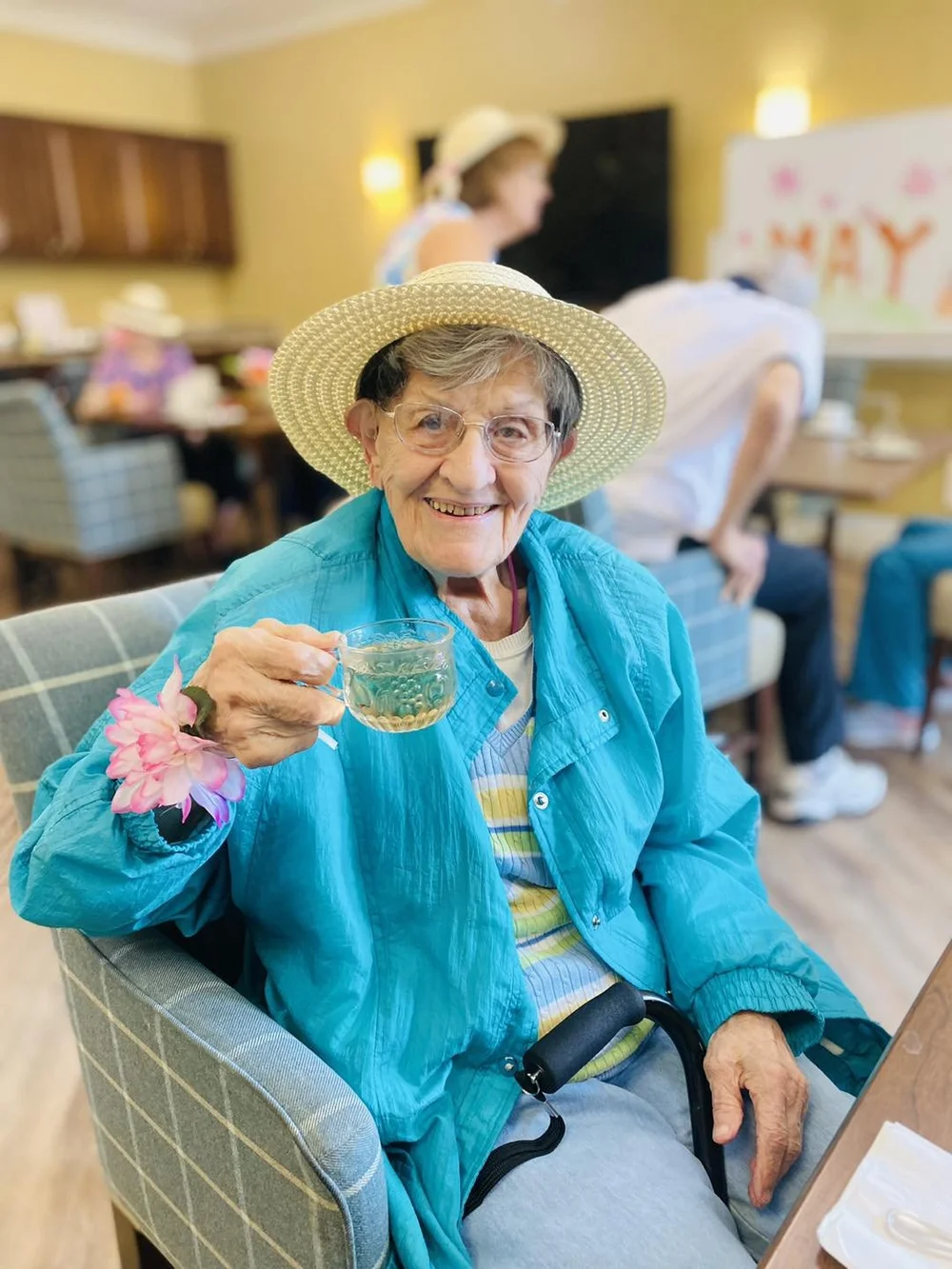 An elderly woman enjoying a drink in a common area