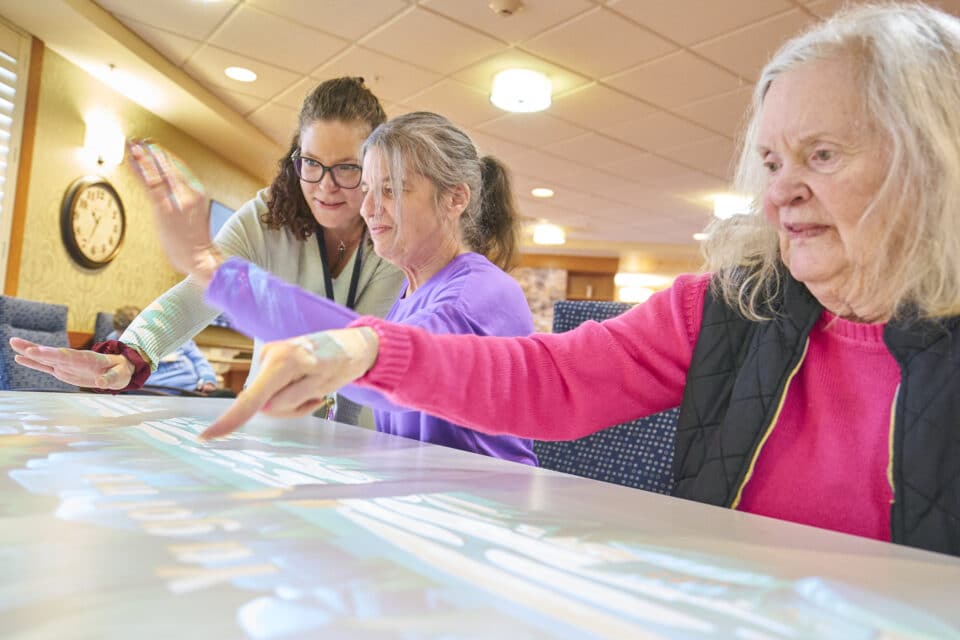 Residents engaging in an interactive activity with staff assistance