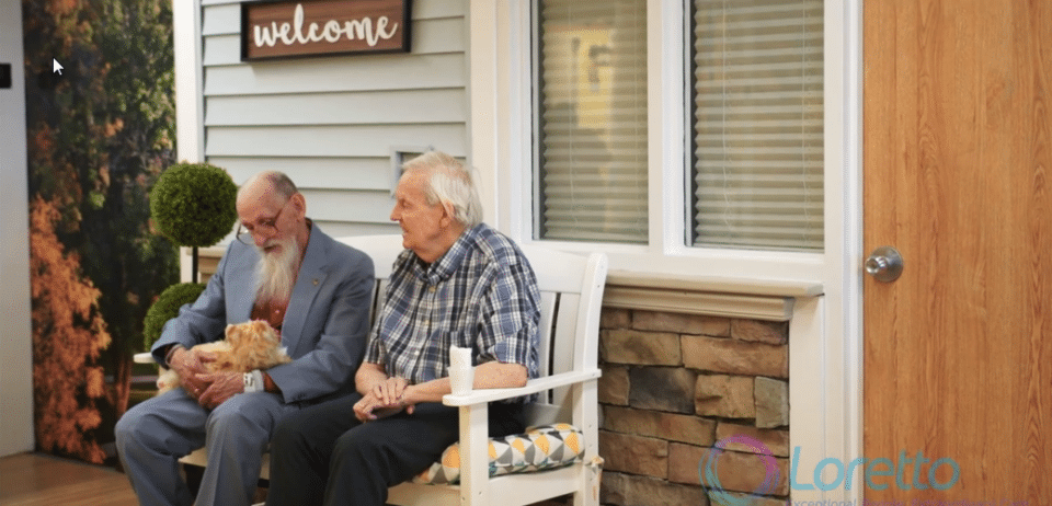 Two men sitting on a bench outdoors with a dog
