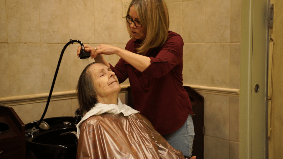 A resident enjoying a hair treatment in the facility salon