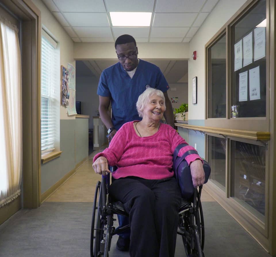 A caregiver assisting a resident in a hallway