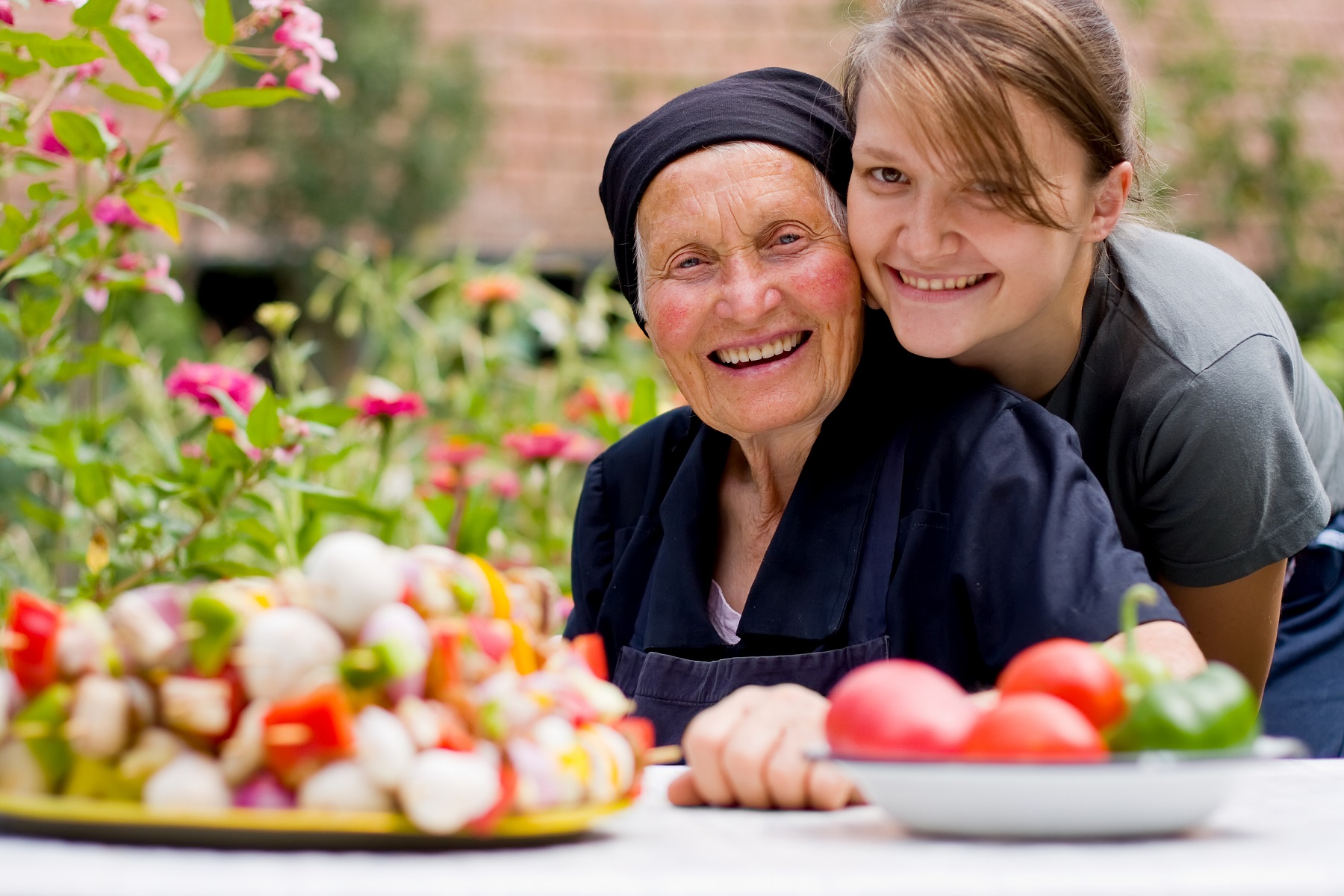 Elderly woman smiling with caregiver in a garden
