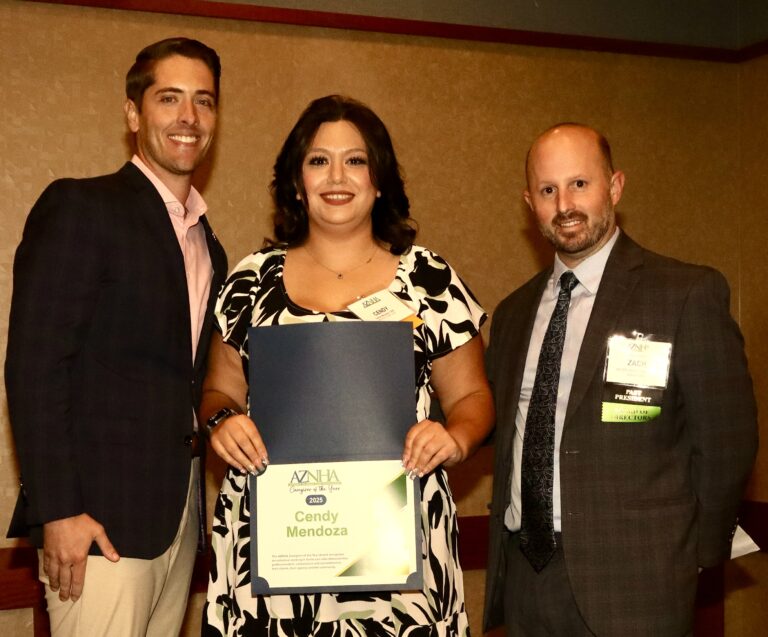 Three individuals at an award ceremony holding a certificate.