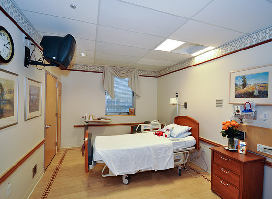 Patient room with a bed and wooden furniture