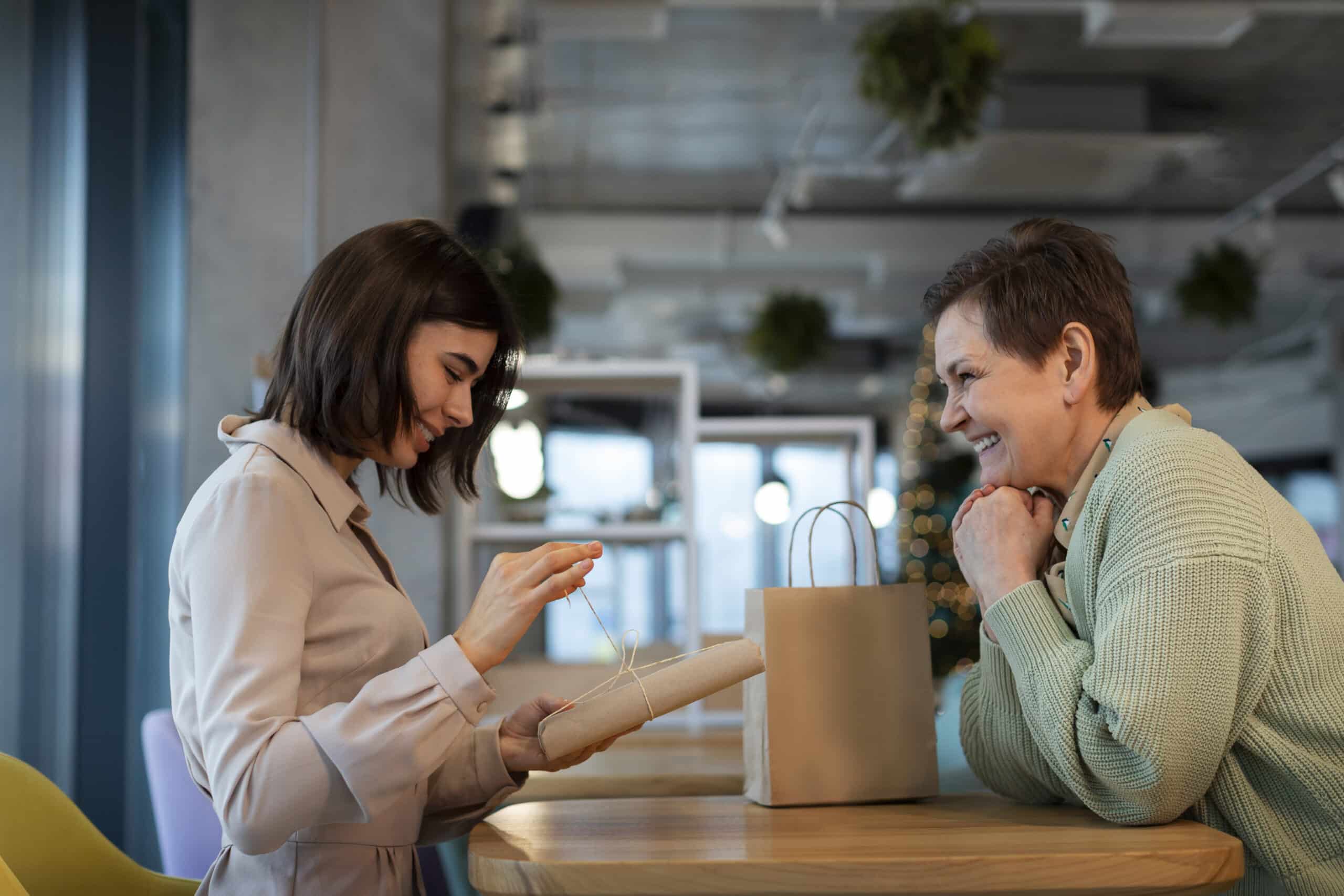 Two women interacting over a gift in a common area.