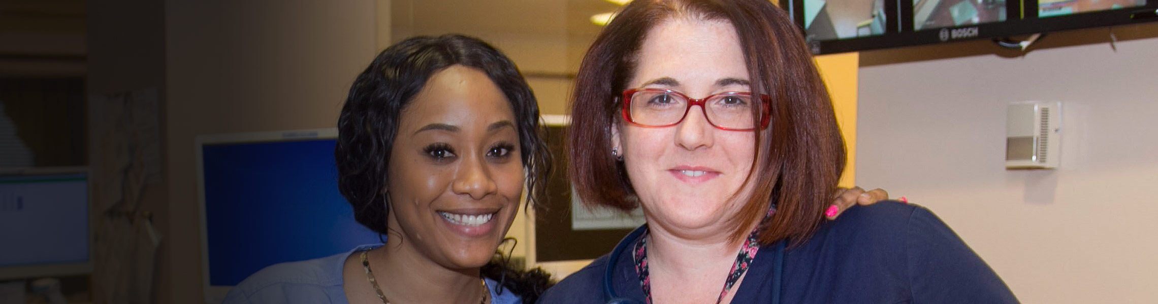 Two staff members smiling together in a facility setting.